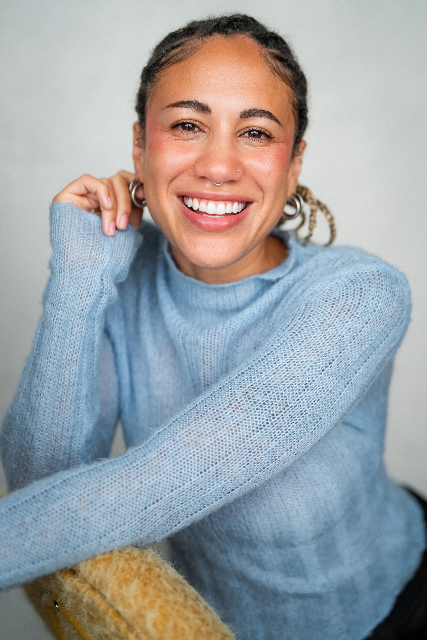 Alexis Kimball laughing, wearing a pale blue mohair sweater, hand resting near her shoulder.